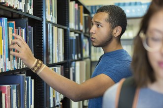 Mixed Race boy choosing book in library