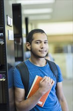 Portrait of Mixed Race boy holding book in library