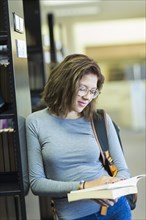 Mixed Race girl reading book in library