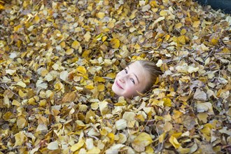 Face of Caucasian girl playing in autumn leaves