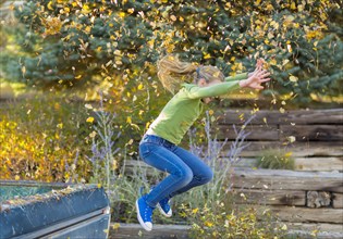 Caucasian girl throwing autumn leaves and jumping off truck