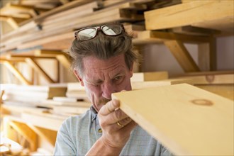 Caucasian carpenter eyeballing wooden plank in workshop