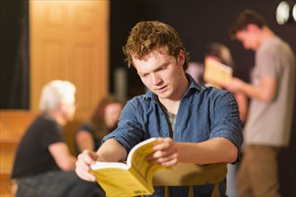 Caucasian teenage boy reading script in theater class