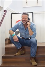 Caucasian man sitting on staircase talking on cell phone