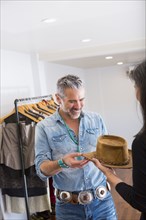 Woman showing hat to man in store