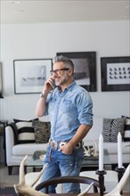 Caucasian man talking on cell phone in livingroom