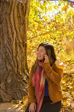 Asian woman talking on cell phone in autumn