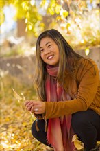 Smiling Asian woman holding leaf in autumn
