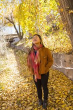 Smiling Asian woman smelling fresh air in autumn