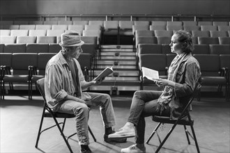 Caucasian actors rehearsing with scripts in theater
