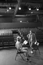 Caucasian actors rehearsing with scripts in theater