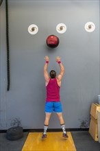 Mixed Race man throwing heavy ball against wall