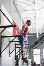 Mixed Race man working out on bars in gymnasium