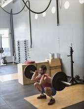 Mixed Race man lifting barbell in gymnasium