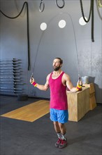 Mixed Race man jumping rope in gymnasium