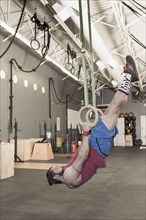 Mixed Race man working out with rings in gymnasium