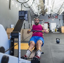 Mixed Race man using rowing machine in gymnasium