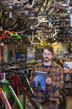 Caucasian worker using digital tablet in bicycle shop