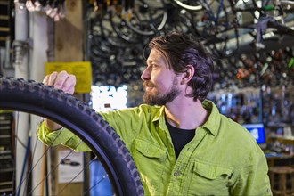 Caucasian worker repairing bicycle wheel in shop