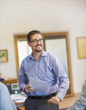 Smiling Hispanic businessman holding paperwork in office