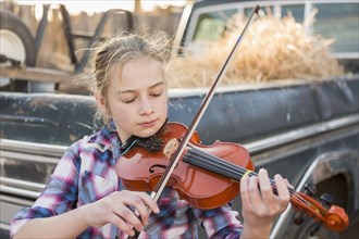 Caucasian girl near truck playing violin