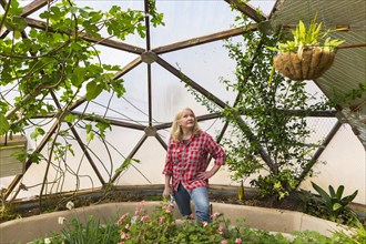 Caucasian woman looking up at hanging plant in greenhouse