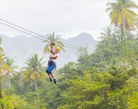 Caucasian girl hanging on zip line in forest