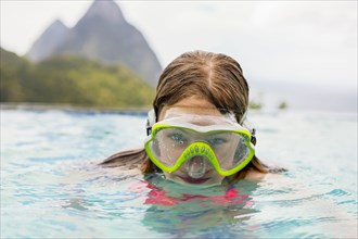 Caucasian girl wearing snorkel mask in swimming pool