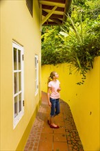 Caucasian girl admiring foliage above yellow wall
