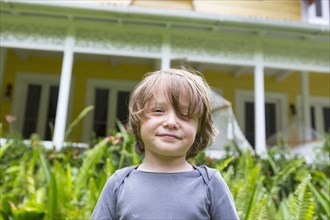 Smiling Caucasian boy in front of house