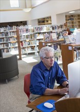 Serious Hispanic man using computer in library