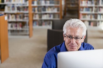 Smiling Hispanic man using computer in library