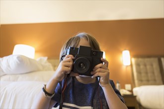 Caucasian boy photographing with camera in hotel room