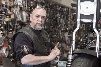 Caucasian man repairing motorcycle and wiping hands