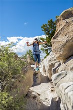 Caucasian girl hiking and jumping near rocks