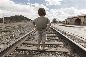 Caucasian boy standing with hands on hips on train track