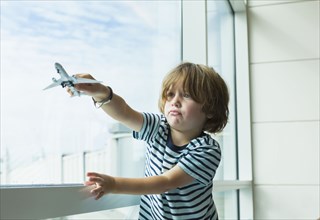 Caucasian boy playing with toy airplane near window