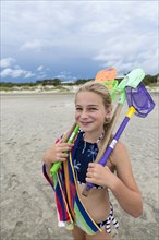 Caucasian girl on beach carrying net and shovels