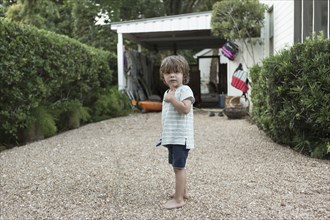 Portrait of curious Caucasian boy standing in driveway