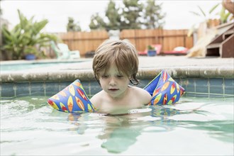 Caucasian boy wearing water wings in swimming pool