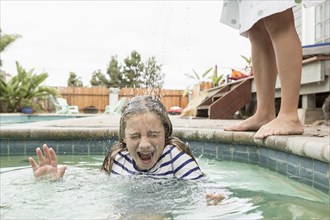 Caucasian boy pouring water on sister in swimming pool