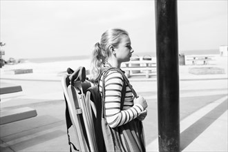 Caucasian girl carrying folding chair at beach