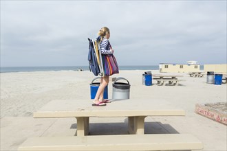 Caucasian girl standing on picnic table at beach