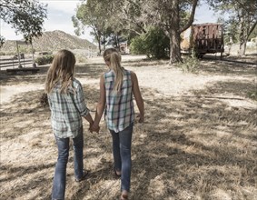 Caucasian girls holding hands walking in field