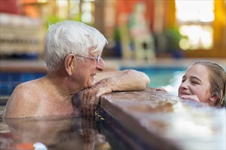 Caucasian grandfather and granddaughter in swimming pool
