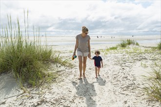 Caucasian mother and son walking on beach