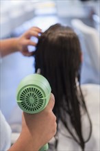 Caucasian stylist drying hair of woman
