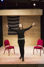 Hispanic woman with arms raised on theater stage