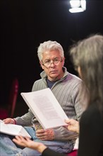Hispanic man and woman reading scripts in theater