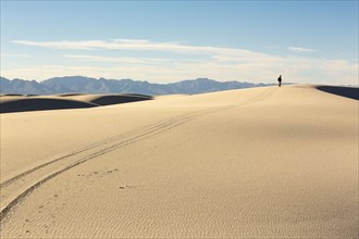 Trail leading to distant Caucasian man in desert